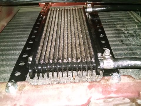 2002 Pontiac Grand Prix - A close-up, low-angle view of an aftermarket transmission cooler mounted in front of a vehicle's radiator. Black hoses with hose clamps con…