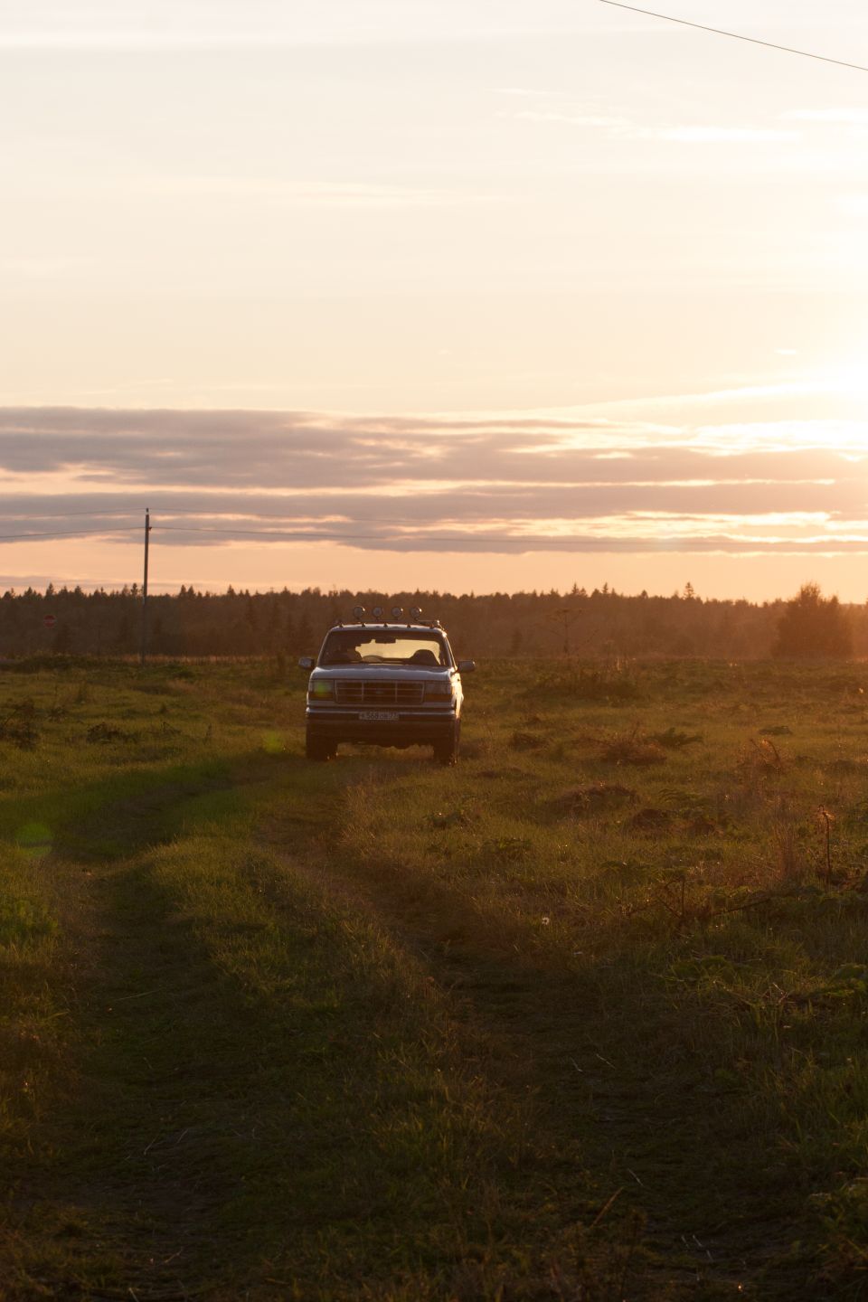 1993 Ford Bronco parked in a field at sunset.