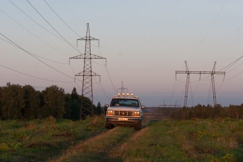 1993 Ford Bronco - A silver Ford Bronco is parked on a dirt road in a grassy field, with power line towers in the background.