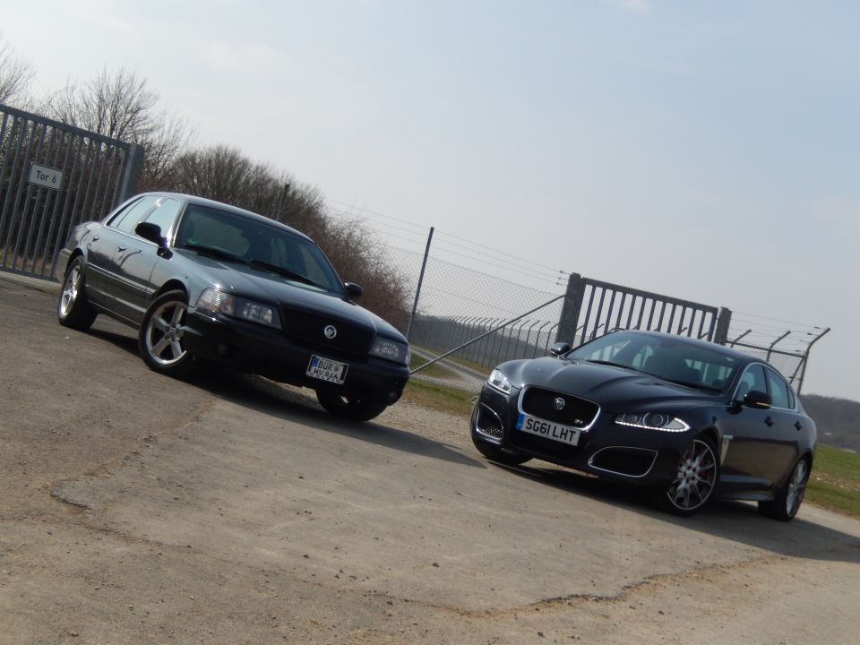 Two black sedans, a Mercury Marauder and a Jaguar XF, parked on a dirt road.