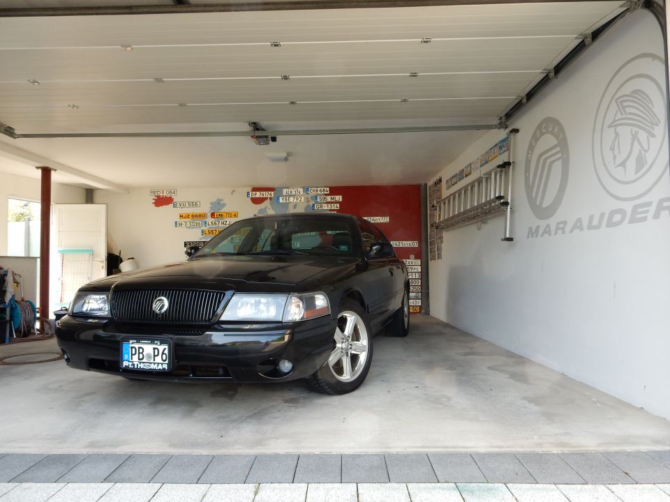 Black 2003 Mercury Marauder parked in a garage with a ladder on the wall and license plates on the back wall