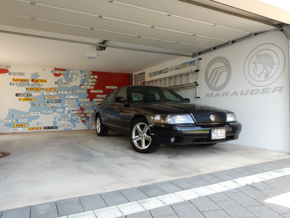 Black 2003 Mercury Marauder parked in garage with license plate wall