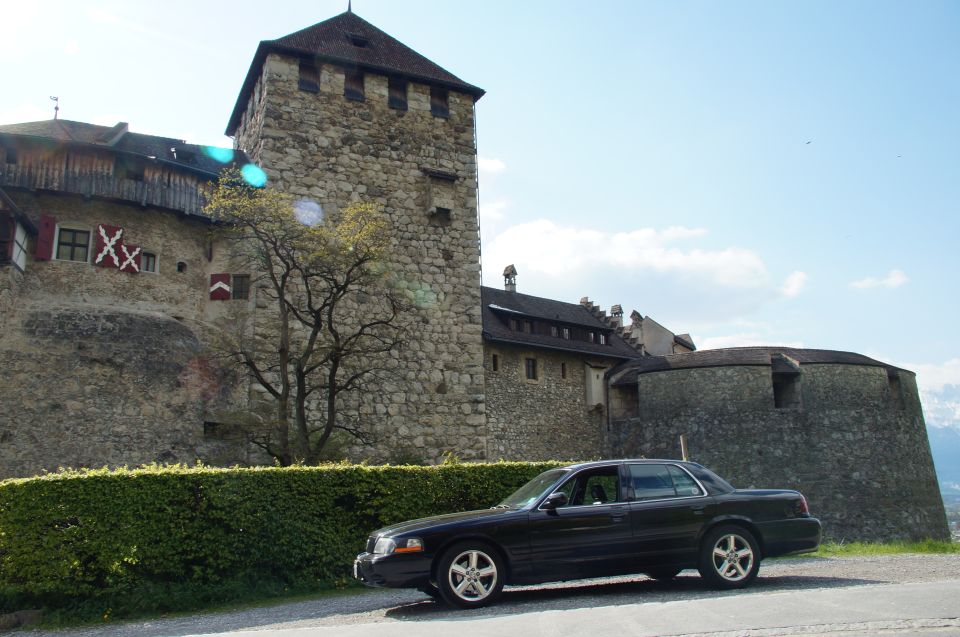 Black 2003 Mercury Marauder parked on a road next to a large stone castle with a tower