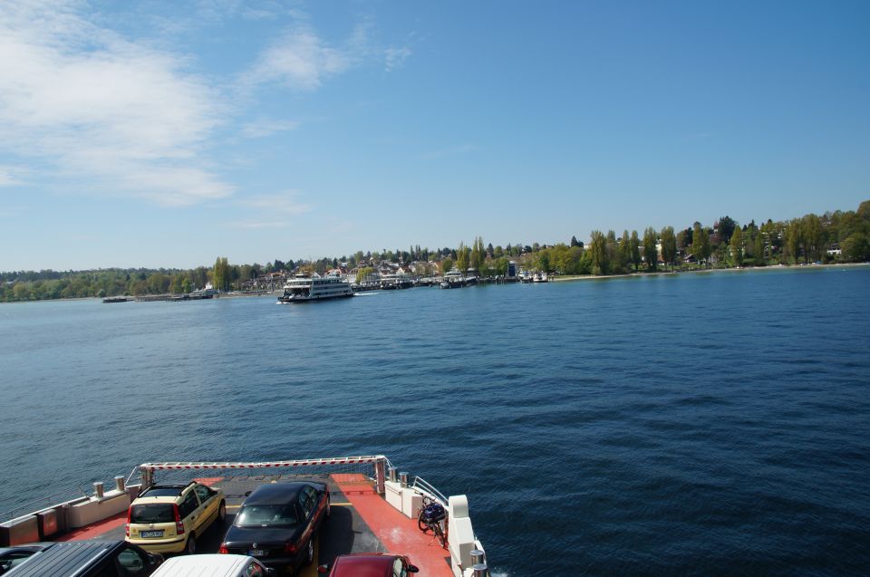 Cars parked on a ferry deck with a body of water and a distant shoreline