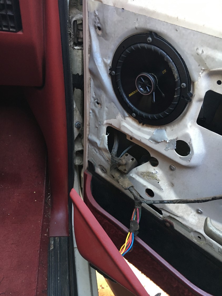 Interior of a car door with the panel removed, showing a Kicker speaker and wiring