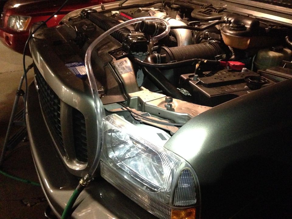 2003 Ford Excursion engine bay with a clear tube connected to the radiator overflow
