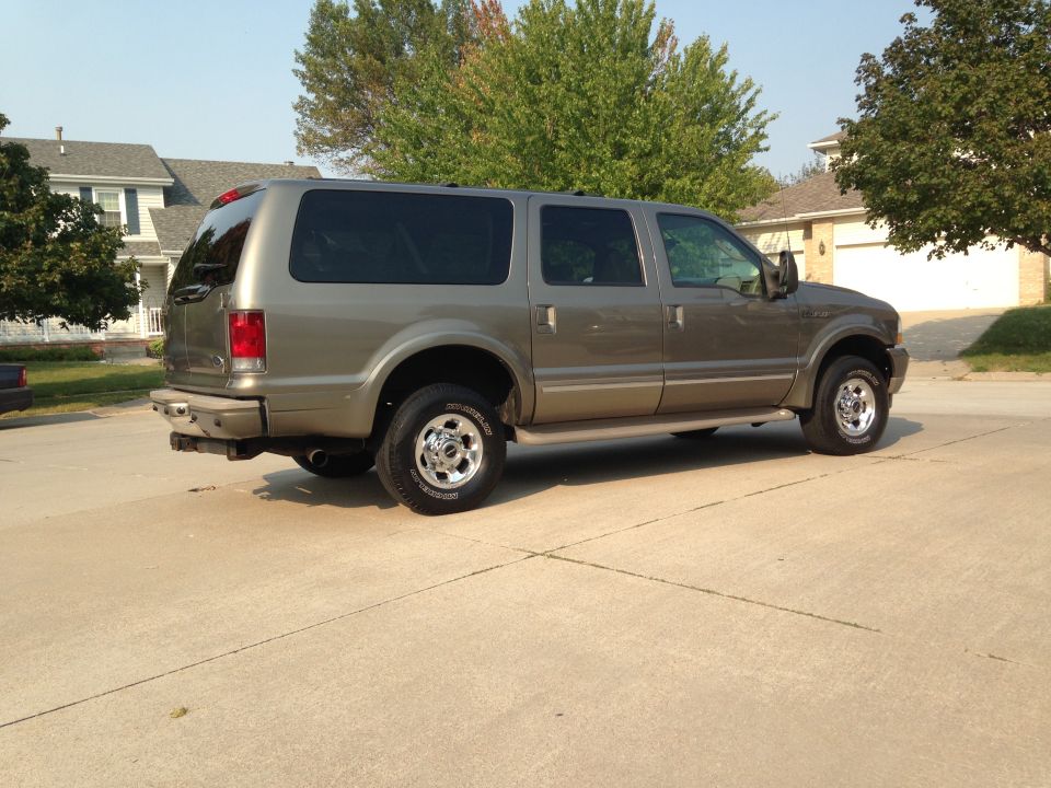 Tan Ford Excursion SUV parked on a paved surface, side view