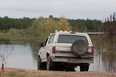 1993 Ford Bronco - A white Ford Bronco is parked near the water's edge, viewed from the rear.