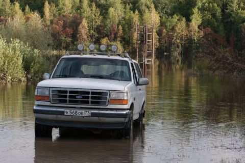 1993 Ford Bronco - A white 1993 Ford Bronco navigates through a flooded road surrounded by trees.
