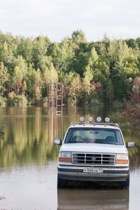 1993 Ford Bronco - A white Ford SUV is partially submerged in water, with a ladder structure visible in the background.
