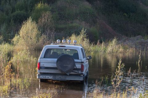 1993 Ford Bronco - This 1992 Ford Bronco is seen from the rear, partially submerged in water with vegetation around it.