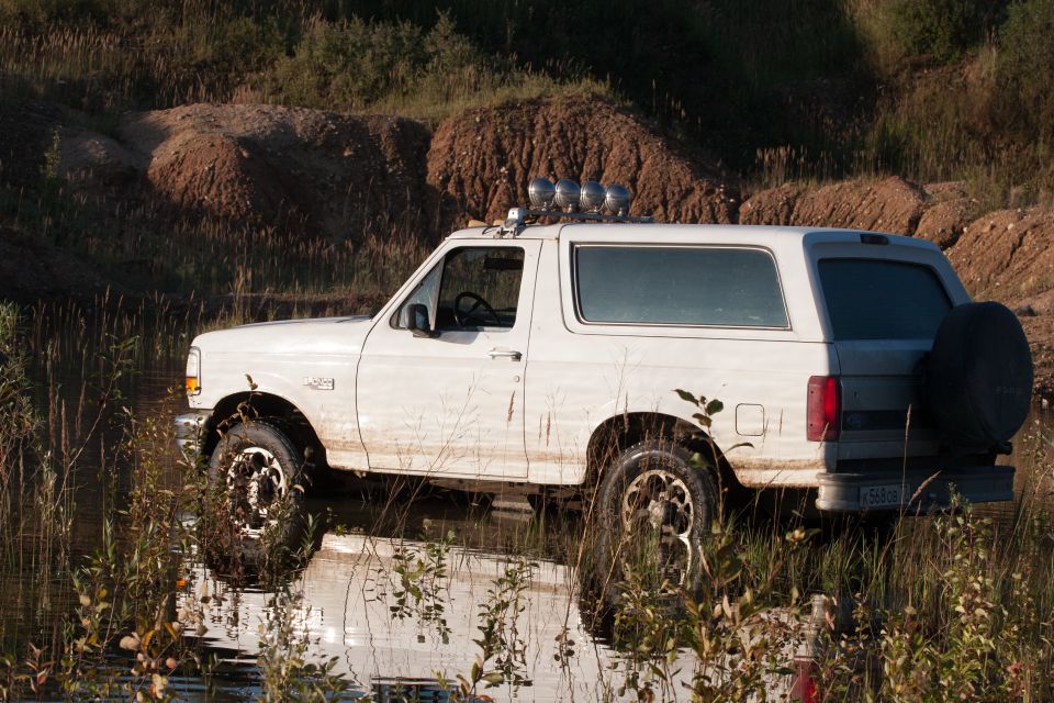 White 1993 Ford Bronco side view, parked in water with off-road tires