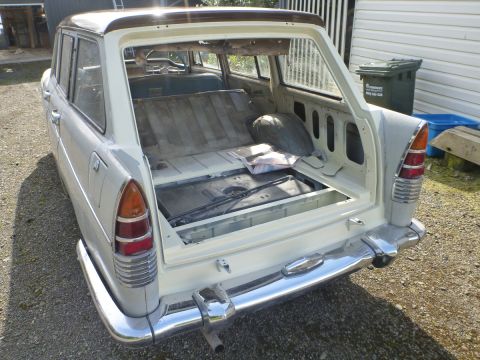 1962 MG B - The rear cargo area of a vintage station wagon is shown with the tailgate open, revealing the interior space.