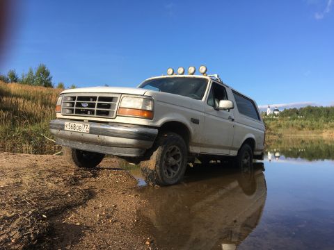 1993 Ford Bronco - This 1993 Ford Bronco is shown off-roading near a body of water under a clear blue sky.
