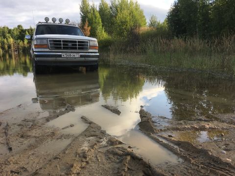 1993 Ford Bronco - White 1992 Ford Bronco navigates through a muddy, water-filled terrain.