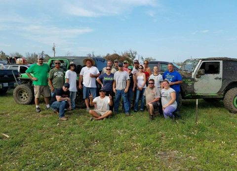 1996 Ford Bronco - A group of people gathered around several off-road vehicles in a grassy, outdoor setting.