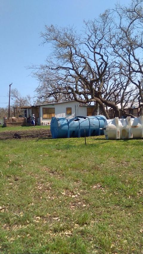 1996 Ford Bronco - Large cylindrical tanks are positioned in a grassy yard near a residential building under a clear sky.
