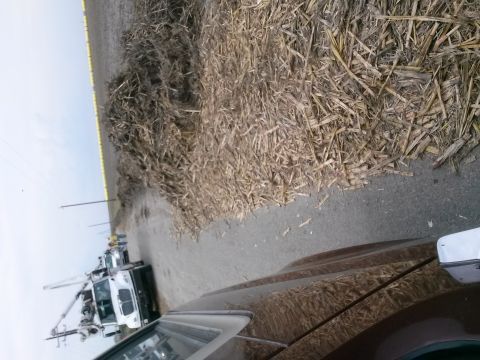 1996 Ford Bronco - A utility truck is parked on the side of a road next to a large pile of dried corn stalks.