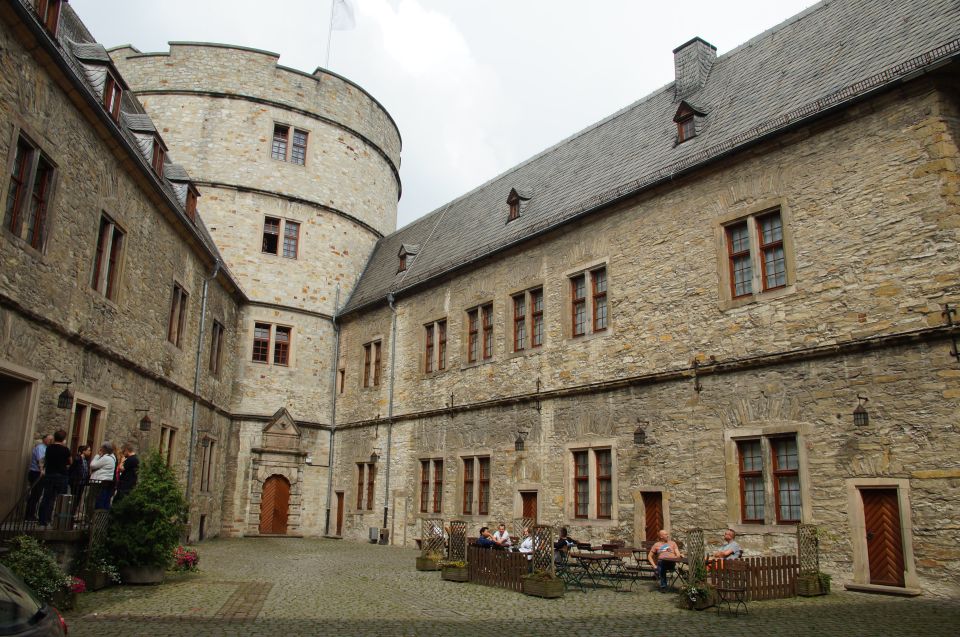 Stone castle courtyard with people gathered and seated at tables