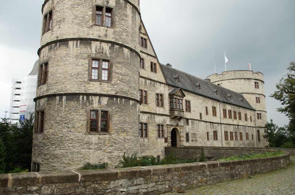 Stone castle with multiple towers and windows, scaffolding on the left side