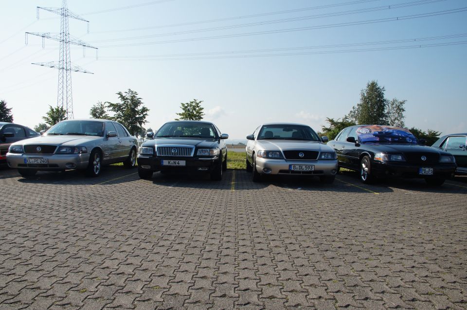 Four Mercury Marauders parked in a lot, one with a colorful decal on its windshield