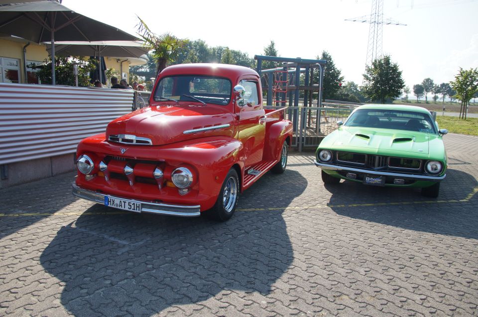 Red pickup truck parked next to a green muscle car