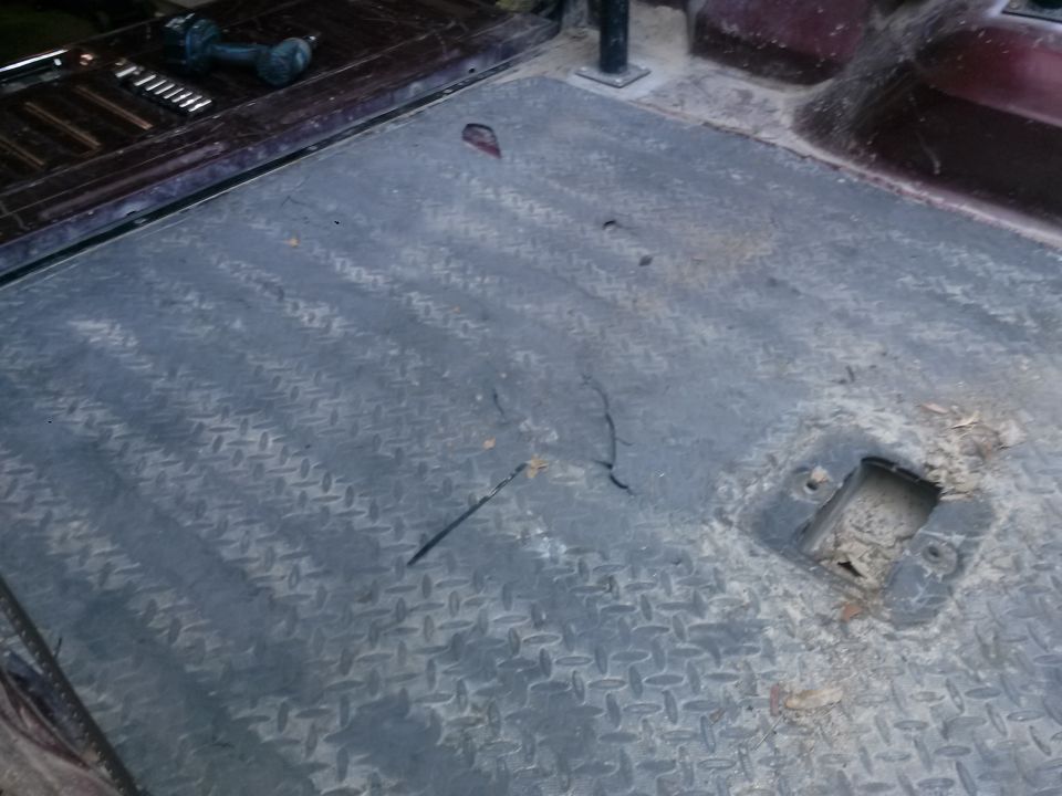 Diamond plate flooring with some debris and a square cutout in a vehicle interior