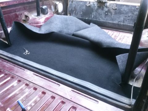 1996 Ford Bronco - Installing new carpet in the rear of a vehicle, with a pair of scissors resting on the material.