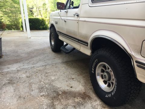 1988 Ford Bronco - This 1988 Ford Bronco is shown from a 3/4 front angle, highlighting its side profile, step bars, and aftermarket wheels.