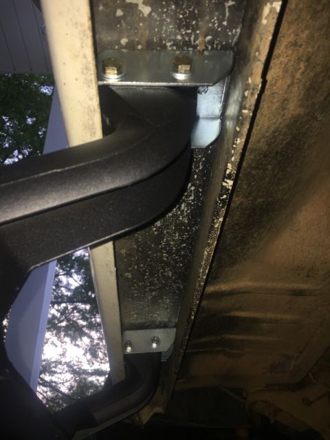 1988 Ford Bronco - Close-up of running board mounting hardware on a vehicle's undercarriage.