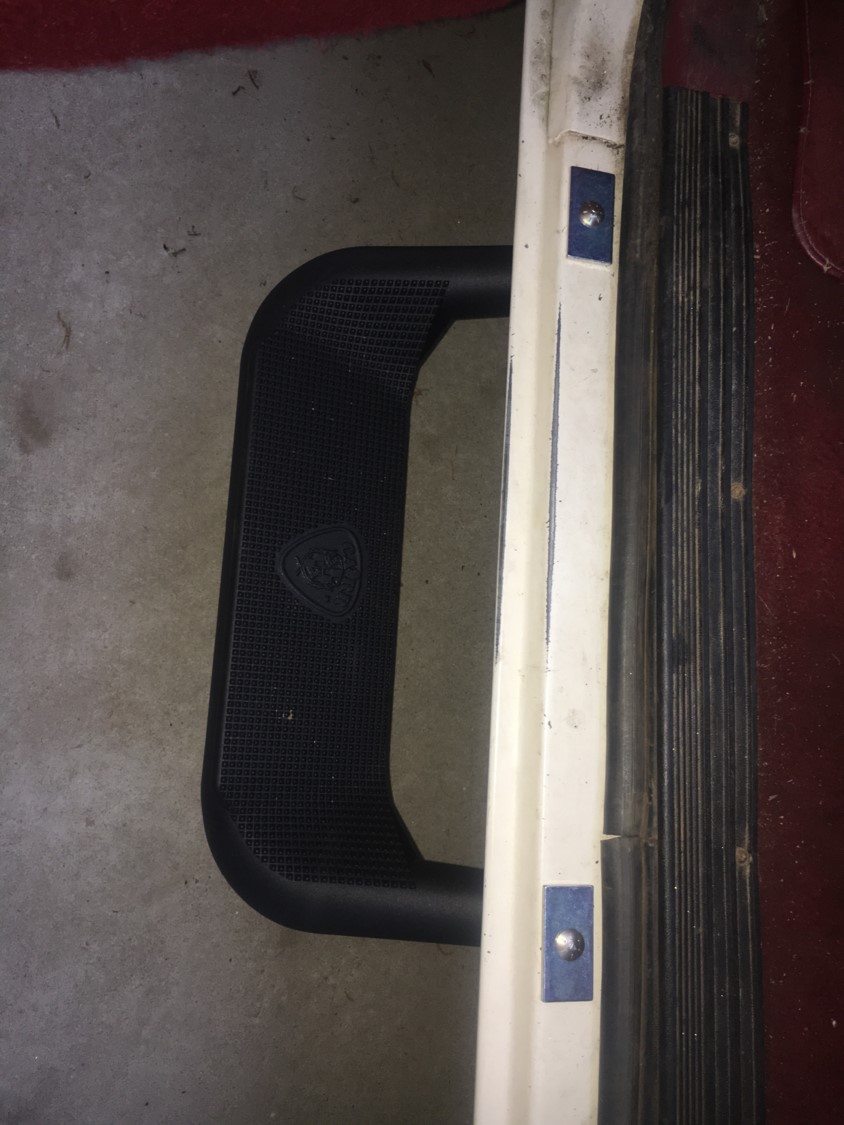 Black step with a logo on it, next to a white trim piece with blue accents