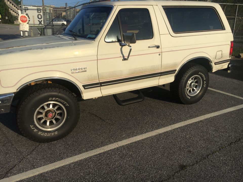 White Ford Bronco with red pinstripes, parked on asphalt