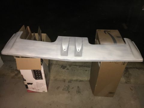 1988 Ford Bronco - A car spoiler is shown resting on several cardboard boxes in a dimly lit area.