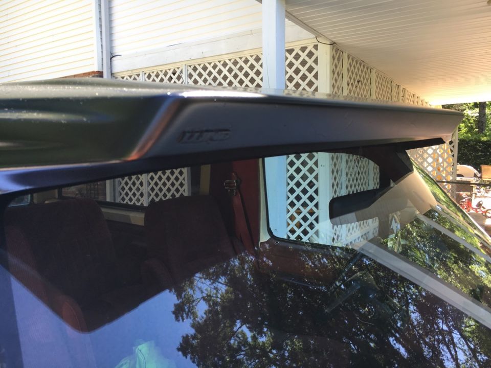Dark rear spoiler with embossed text above rear window of an SUV