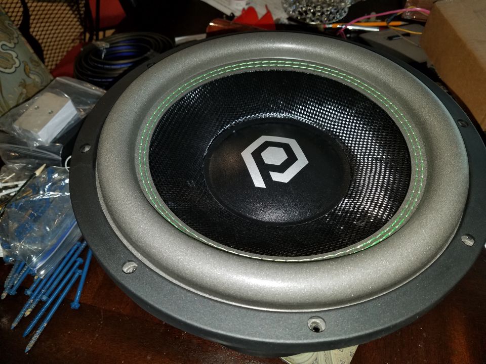Subwoofer with a silver surround and black cone, a hexagonal 'P' logo