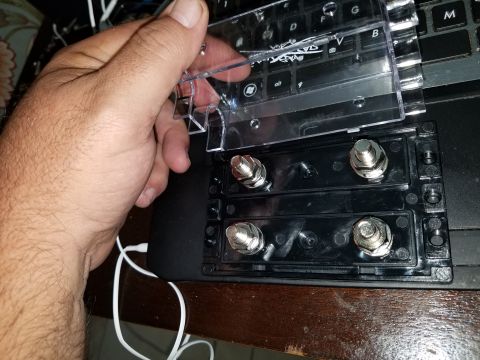1994 Ford Bronco - Car stereo power distribution block with a clear protective cover being held.