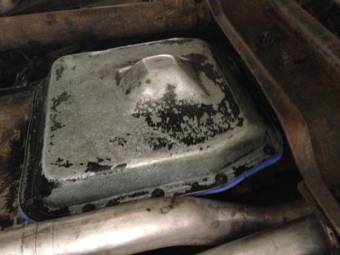 1986 Ford Bronco - Underside view of a vehicle's oil pan, showing a blue gasket and signs of wear.