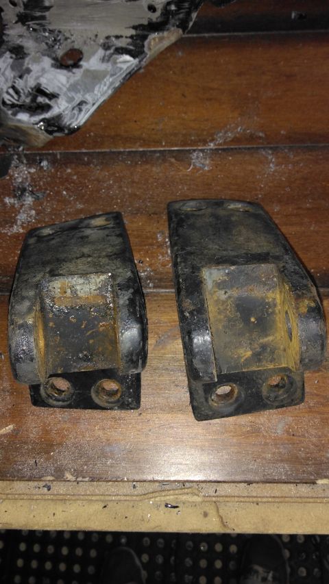 1996 Ford Bronco - Two heavily rusted metal brackets are shown, each with two visible bolt holes.