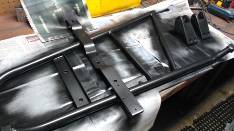 1996 Ford Bronco - Metal parts, possibly for a vehicle, are laid out on newspaper and appear to be freshly painted.