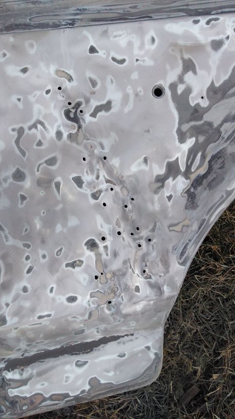 1996 Ford Bronco - A car door is covered in body filler and has many small holes, indicating it is undergoing repair work.