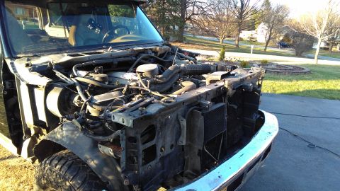 1996 Ford Bronco - The front end of a truck is shown with its hood and grille removed, revealing the engine and radiator components.