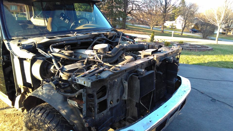 Disassembled front end of a truck with engine exposed. SuperMotors logo visible