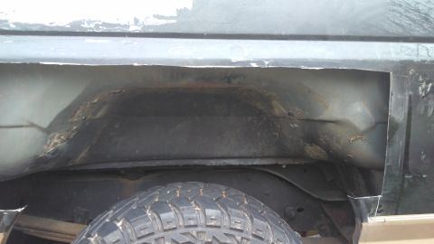 1996 Ford Bronco - The rear wheel well of a vehicle has been cut open, revealing rust and damage to the inner body panels.