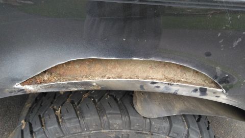 1996 Ford Bronco - Rusted wheel well opening on a vehicle, showing damage and debris.
