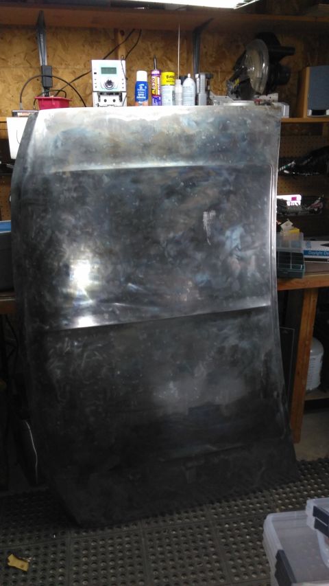 1996 Ford Bronco - A bare metal hood, likely undergoing restoration or preparation for paint, is shown in a workshop setting.