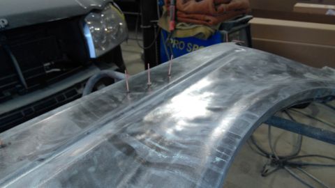 1996 Ford Bronco - A car fender is shown with metal pins inserted, likely for bodywork or repair.
