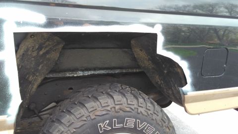 1996 Ford Bronco - Detail of the rear wheel well and frame, with primer applied to the body panel.