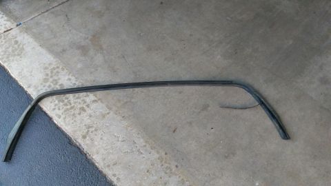 1996 Ford Bronco - A detached rubber seal, likely for a car window, lies on a concrete surface.