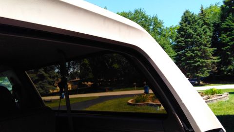 1996 Ford Bronco - Looking out the side window of a vehicle at a residential area with trees and a street visible.