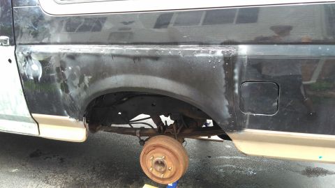 1996 Ford Bronco - The rear wheel well of a Ford Bronco shows signs of body repair and rust, with the drum brake visible.